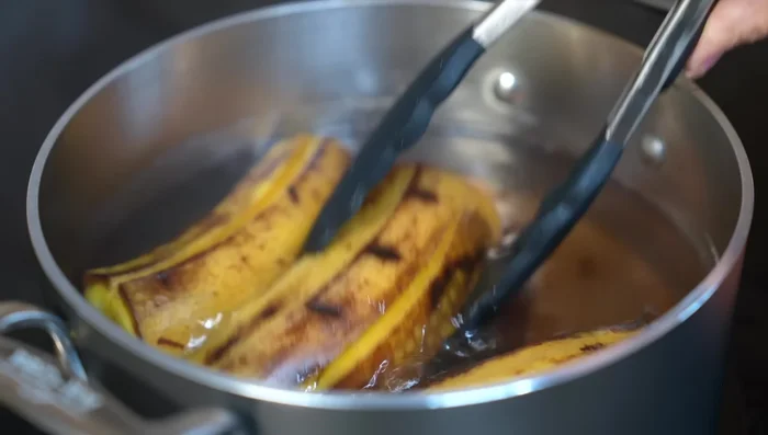 After 15 minutes, remove plantains from the pot. Once lukewarm, peel and cut in half, removing seeds.