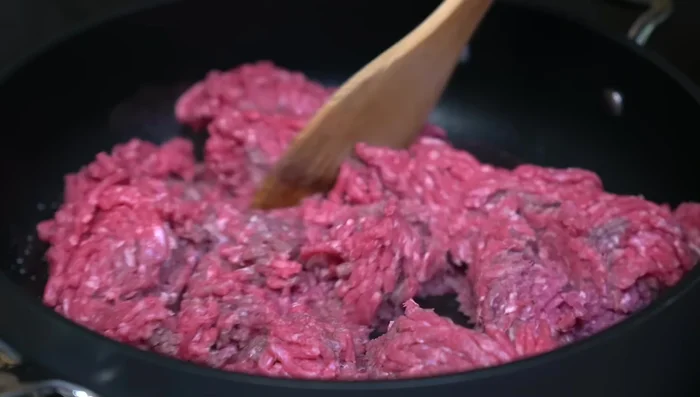 In a hot pan with a little oil, fry the seasoned ground beef until cooked through. Add chopped garlic during cooking.