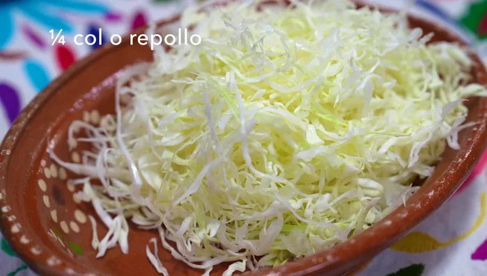 Prepare the coleslaw: Slice cabbage and red onion thinly. In a container, mix mayonnaise, taco cream, sesame oil, toasted sesame seeds, lemon juice, salt, and broken chile de árbol.