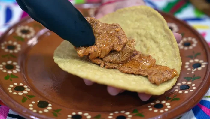 Assemble the tacos: Fill each tortilla with a generous portion of cooked pork, coleslaw, creamy green chile sauce, and avocado slices.