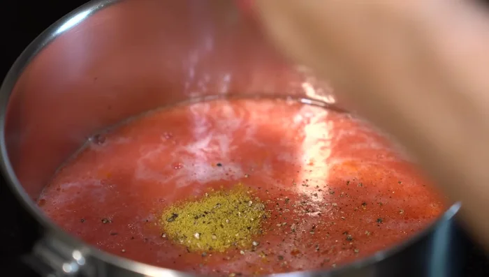 In a saucepan with a little hot oil, cook the blended tomato mixture. Season with salt, chicken bouillon powder, pepper, and oregano. Simmer for 5 minutes.