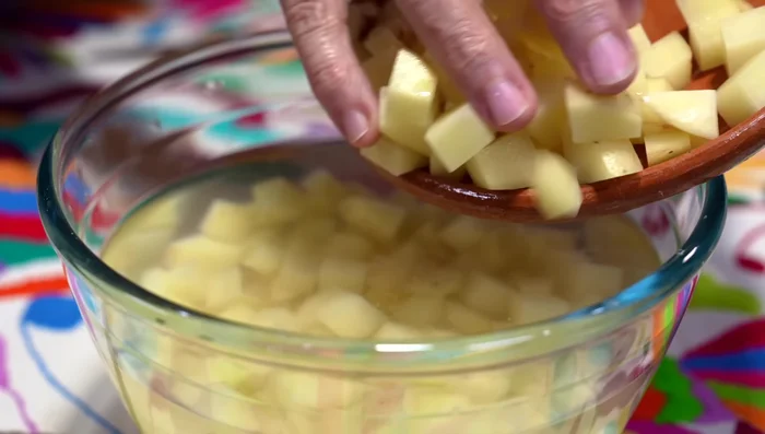 While the beef cooks, prepare the potatoes by cutting them into cubes and keeping them in water to prevent discoloration.