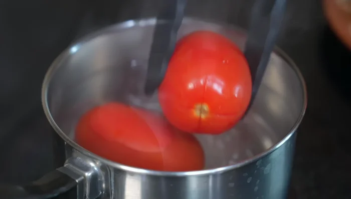 Poach the tomatoes in boiling water for a couple of minutes to easily remove the skins. Peel the tomatoes.
