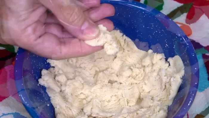 Prepare corn dough ears (chochoyotes): Mix dry tortilla dough, lard, salt, and chopped pasote or hoja santa. Roll into small balls and press in the center to form a small cup shape.