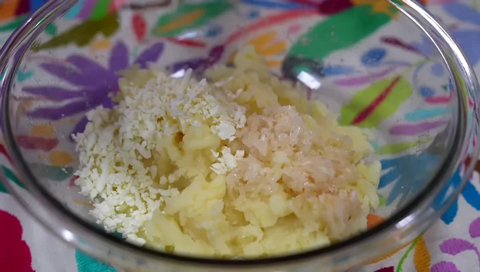 Mix mashed potatoes with sautéed onion, grated cheese, chopped bacon, parsley, salt, pepper, and beaten egg. Add breadcrumbs for binding. Mix well.
