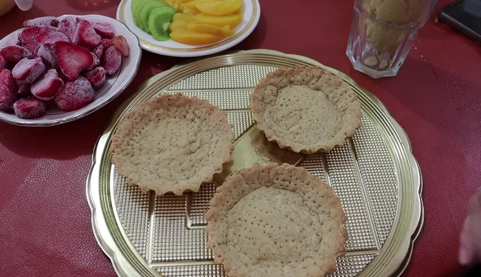 Assemble the tartlets: Fill tart shells with pastry cream. Arrange sliced peaches, kiwi, and strawberries on top, creating a decorative design.