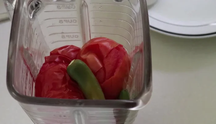 Blend the cooked tomatoes, green chilies, garlic, half an onion, and salt.