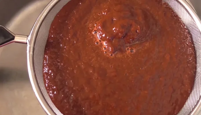 Strain the blended mixture into a saucepan. Add 2 tablespoons of vinegar and simmer.