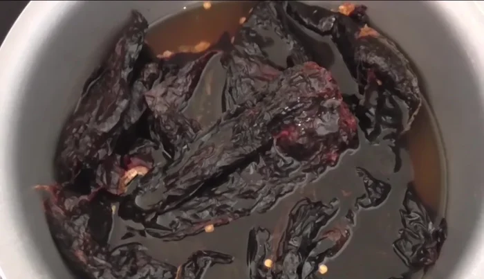 In a separate saucepan, boil the dried pasilla chilies for hydration. After 10 minutes, remove and let rest.