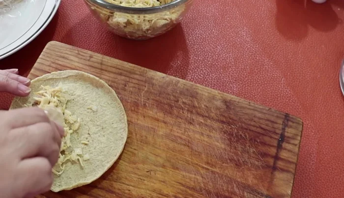 Place shredded chicken on warm tortillas, roll them up to form flautas.