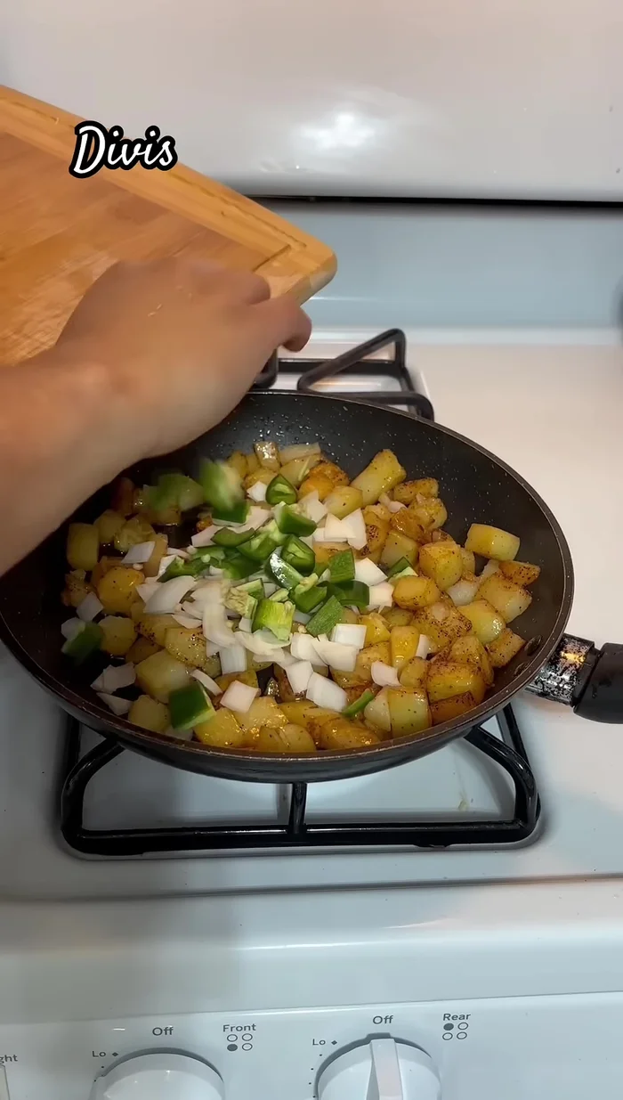 Add onion, chili, and tomato to the cooked potatoes.