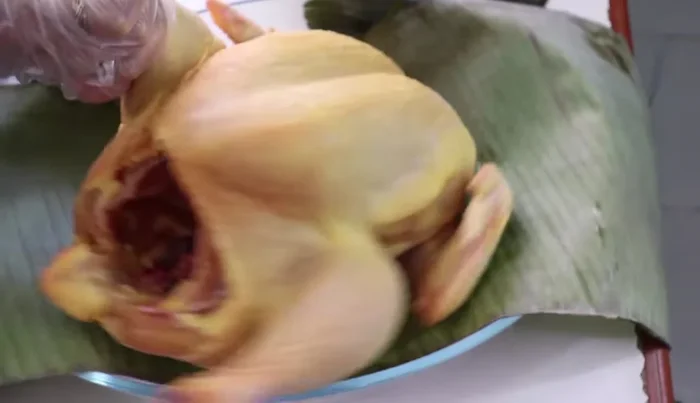 Marinate the chicken: Place the washed chicken in a mold lined with a banana leaf. Season with salt and herbs, then rub the marinade all over the chicken. Let it marinate overnight or at least 2-3 hours in the refrigerator. (126, 252.439, 297.16, 331.039)