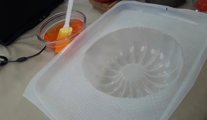 Layer the gelatin: Remove the mold from the freezer. Add a layer of assorted fruits, some peach slices, and a cherry. Carefully pour in a layer of the transparent gelatin, ensuring it doesn't disturb the fruit. Freeze for a few minutes to set. (277.56)