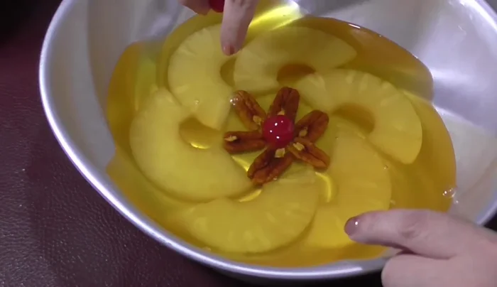 Add cherries: Cut cherries in half and place them upside down in the pineapple slices.