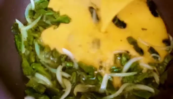 Pour the beaten eggs over the Rajas and onion mixture. Cook until eggs are set (206.84).