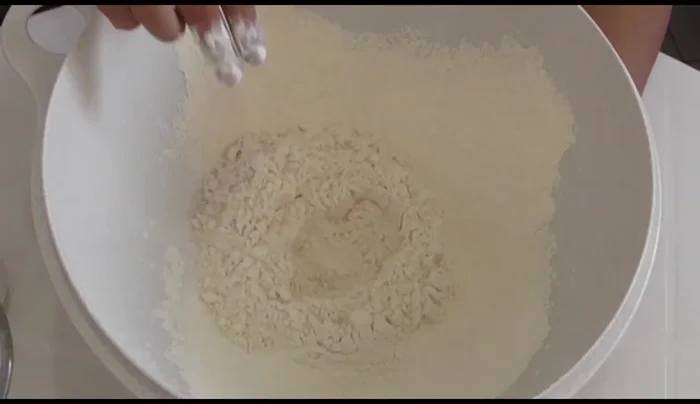 Make a well in the flour. Add sugar, egg, melted butter, salt, warm water, and yeast.