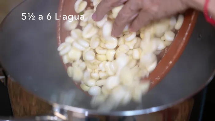 Cook corn for Red Pozole: Cook corn in boiling water until it begins to pop. Add onion, halved garlic heads, and salt. Cover.