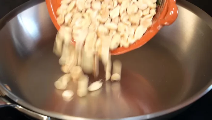 Toast the peanuts in a hot pan until lightly browned, stirring constantly to prevent burning.
