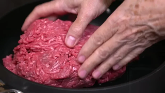 In a separate hot pan with a little oil, brown the ground beef. Season with salt and pepper. Add a chopped garlic clove for extra flavor.