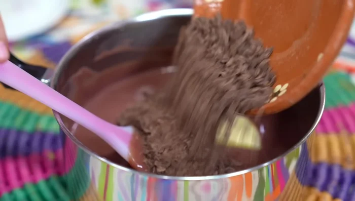 Add butter, chopped chocolate, and vanilla extract to the hot mixture. Stir until fully incorporated.