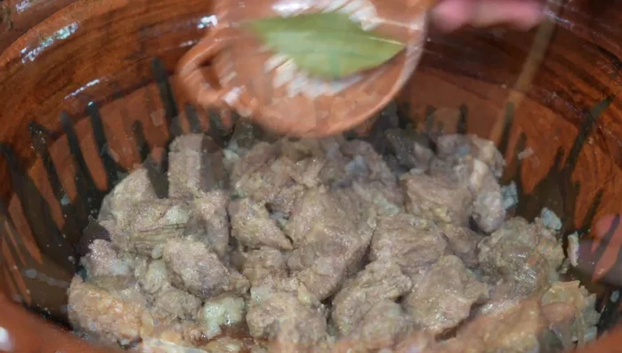 Add bay leaf and the chipotle paste to the meat.