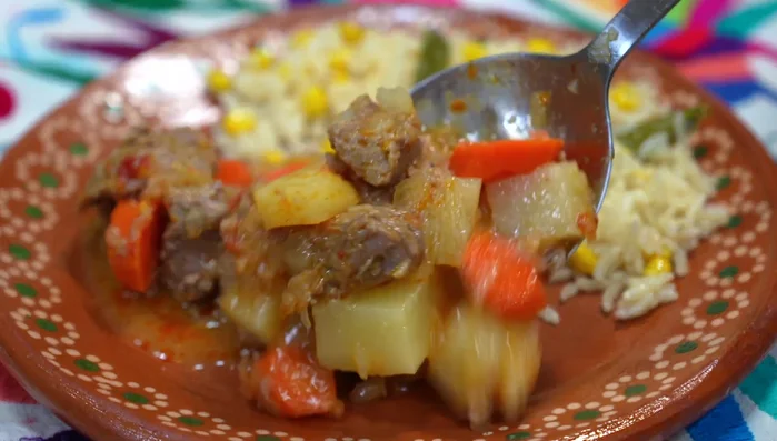 Serve the tender orange pork with rice, corn, and rajas.