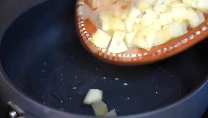 Fry cubed potatoes with salt until slightly cooked. Add sliced onions and continue frying.