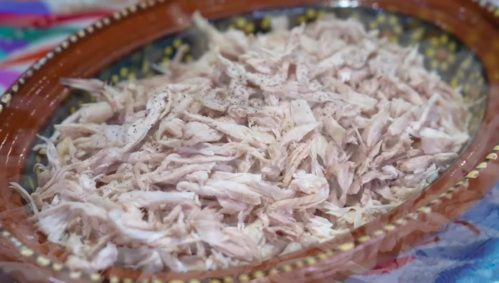 Season shredded chicken with salt, pepper, and flour. Mix well.