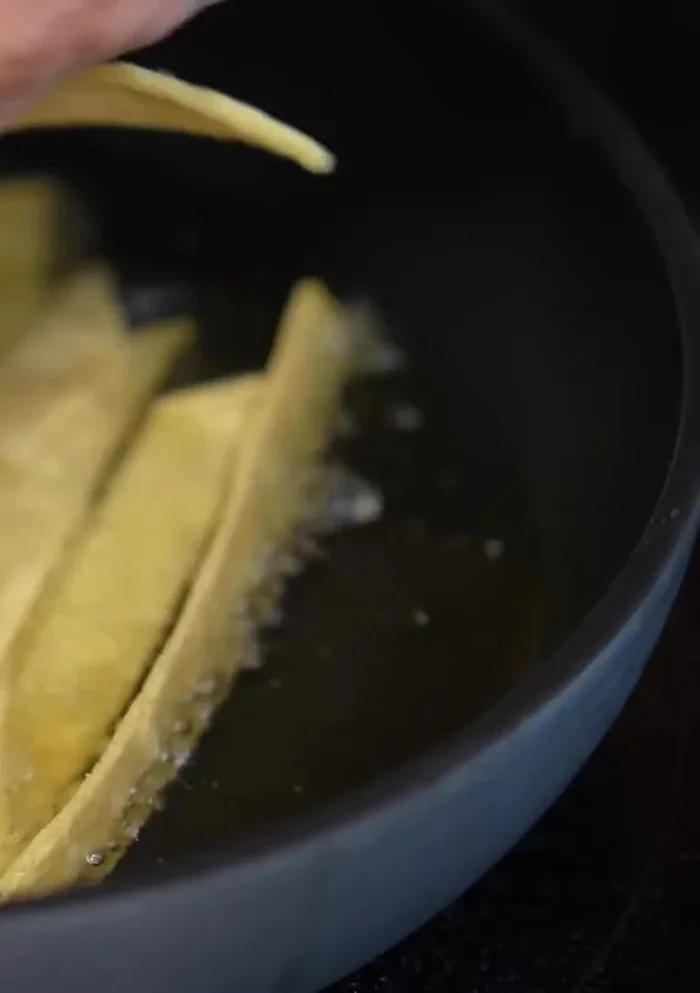 Fry the corn tortillas until golden brown.
