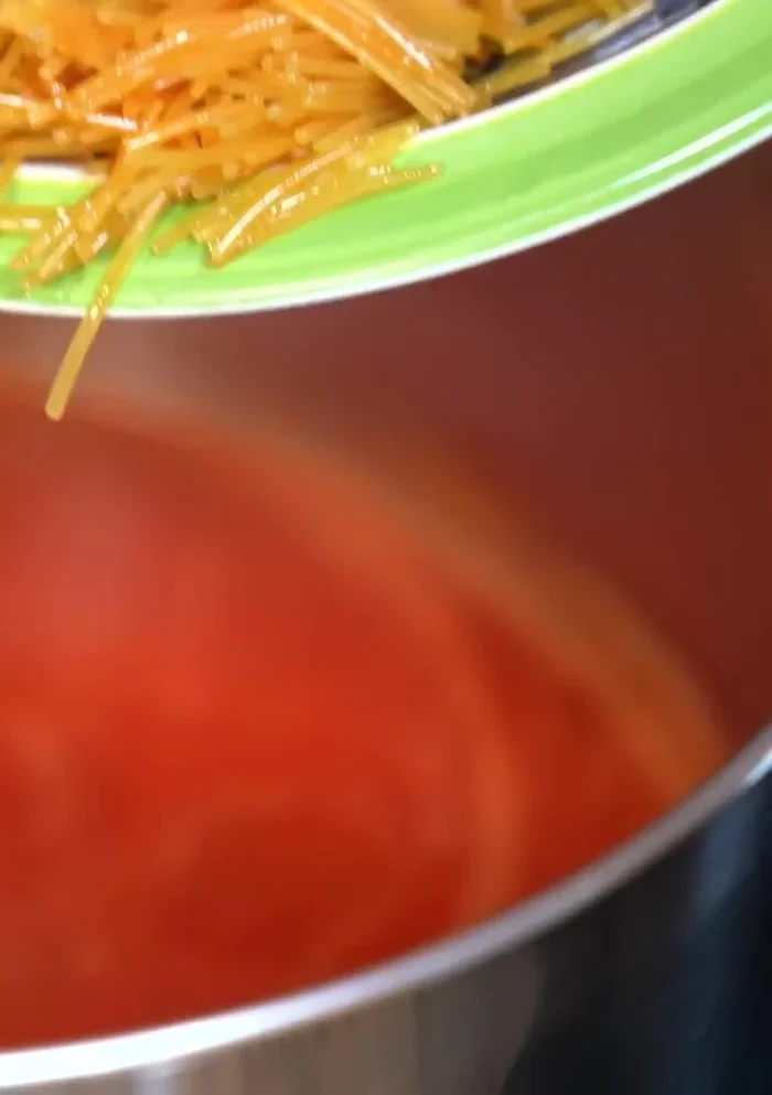 Add the fried noodles and warm chicken broth to the tomato sauce. Bring to a boil.