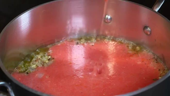 Pour in blended tomatoes and simmer for 5 minutes. Add tomato puree, salt, and stir. Reduce heat and let flavors integrate.