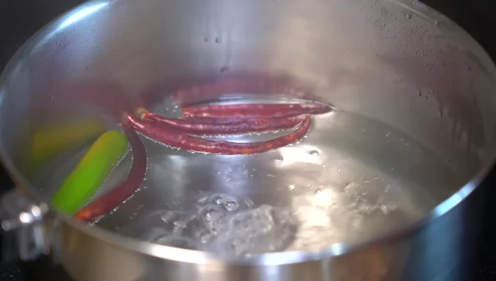 Cook chilies in boiling water, then add tomatoes and green tomatoes. Blend the mixture with onion, garlic, and a little cooking water.