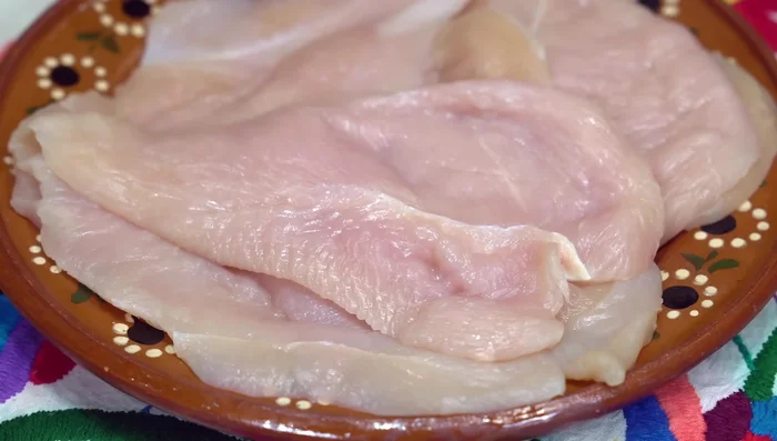 Marinate chicken breast with garlic, salt, pepper, mustard, paprika, soy sauce, lemon juice, water, and olive oil.