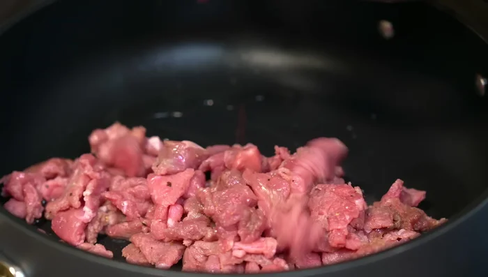 In a hot pan, sear the meat over high heat. Add chopped garlic. Lower heat and cover, adding water as needed.