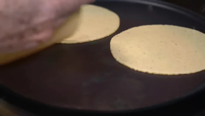 Serve the nopales pancakes warm, dipped in the tomato broth, and accompanied by refried beans and corn tortillas.