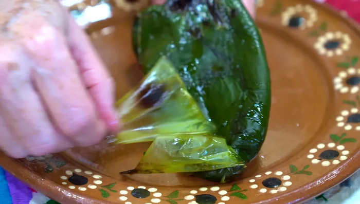 Remove the seeds and cut the roasted poblano peppers into strips.