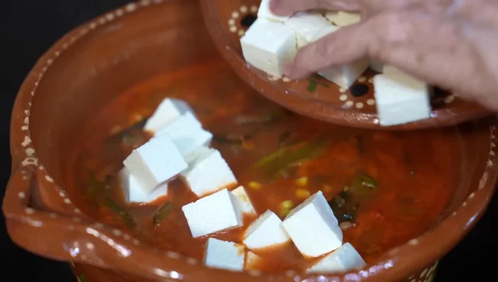 Add the cheese, cut into pieces. Cover and heat until the cheese is melted and softened (a few minutes).
