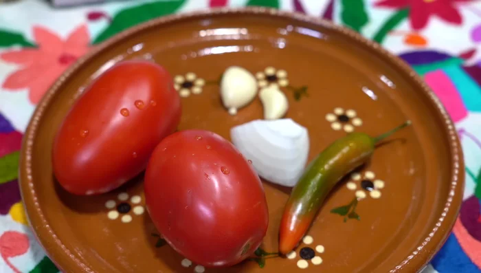 Prepare the tomato sauce: Boil three chopped tomatoes, a serrano pepper, a small piece of onion, and two cloves of garlic until soft (approximately 8 minutes).