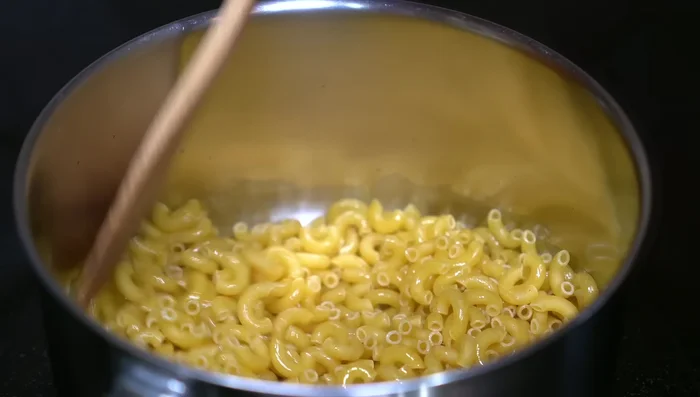 Fry elbow macaroni in hot oil until golden brown, stirring constantly to prevent burning.