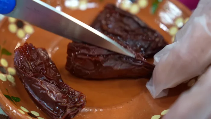 Remove seeds and veins from the chiles (optional). Blend the chiles, onion, raw garlic, some of the meat broth, and the molcajete paste.