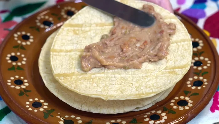Warm a tortilla and spread with refried beans. Place it on top of the egg mixture with beans facing down.