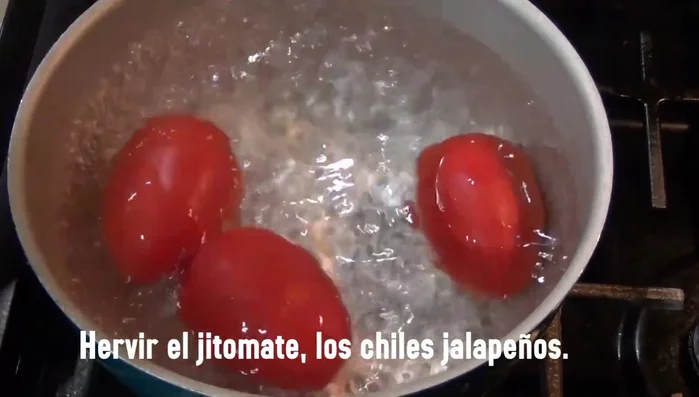 Boil tomatoes and jalapeño peppers in water.