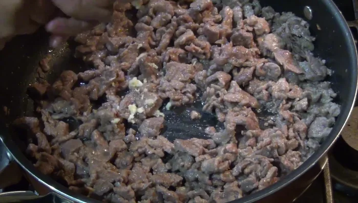 Add the pressed garlic, ground pepper, and bay leaf to the cooked beef.