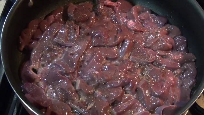 Add sliced onions, garlic, and serrano chilies to the pan, along with pepper and salt to taste. Cook until the onions are softened and the chilies are slightly charred.