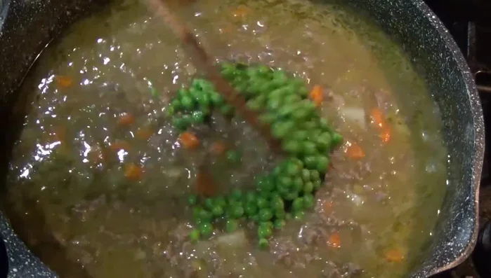 After approximately 15 minutes, add the peas. Simmer for another 5 minutes.