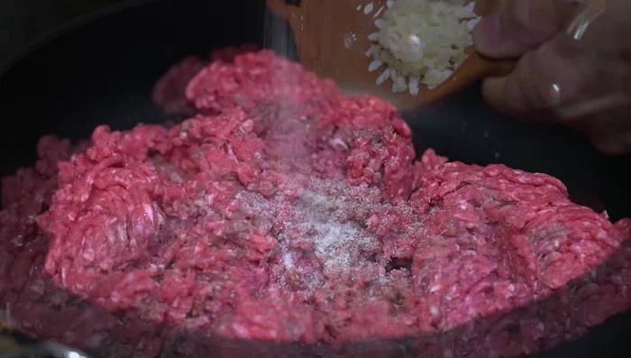 Add chopped garlic and stir constantly to break down the meat and cook evenly.