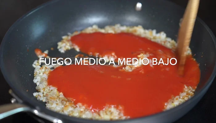 Add canned tomato puree. Lower heat to medium-low and sauté.