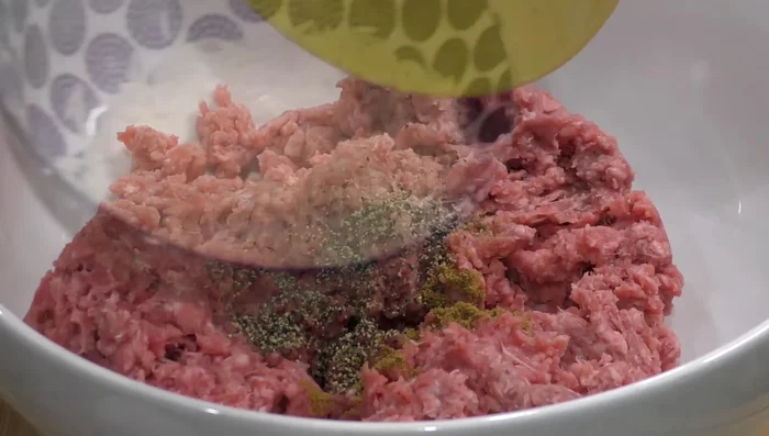 In a bowl, combine ground beef, cumin, pepper, rice, cilantro, egg, and salt. Mix well.