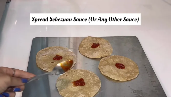 Spread Schezwan sauce on each roti.