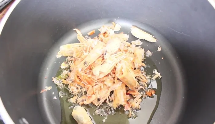 Fry the ingredients: In a saucepan, heat olive oil and add dried shrimp tails and heads, then fresh shrimp heads. Fry until fragrant and shrimp change color. Add the chopped onion and fry until softened.